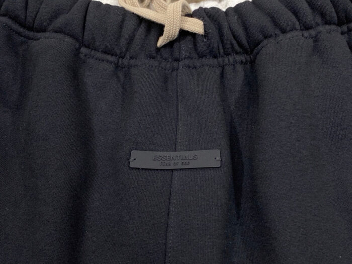 Pantaloni jogger neri con elastico, cordino beige e dettaglio minimalista elegante.