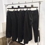 Primo piano di pantaloni neri casual e sportivi su rack metallico con appendini in legno