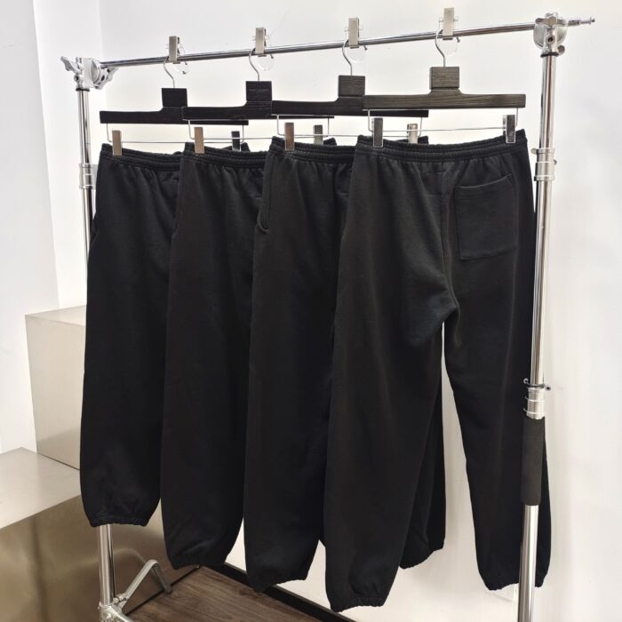 Primo piano di pantaloni neri casual e sportivi su rack metallico con appendini in legno