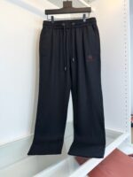 Pantaloni felpati neri moderni con tasche, elastico regolabile e logo ricamato.