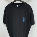 T-shirt nera casual con logo blu stylizzato, vestibilità oversize, ideale per look moderni e confortevoli.