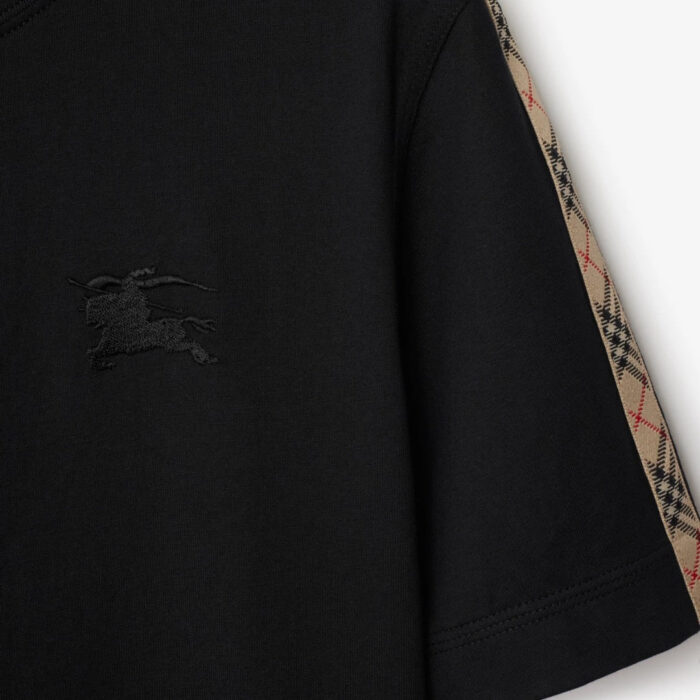 T-shirt nera con dettagli Burberry, logo tono su tono e maniche con motivo a quadri.