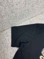Manica di maglietta nera in cotone, dettaglio morbido e sartoriale su sfondo leggero.