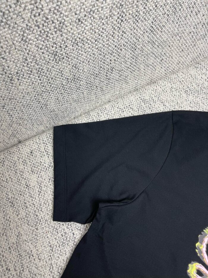 Manica di maglietta nera in cotone, dettaglio morbido e sartoriale su sfondo leggero.