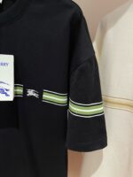 Maglietta nera sportiva con strisce verde e bianca, dettaglio sul colletto e tessuto leggero.