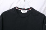 Maglietta nera Thom Browne con dettaglio colorato e logo premium, stile minimalista e versatile.