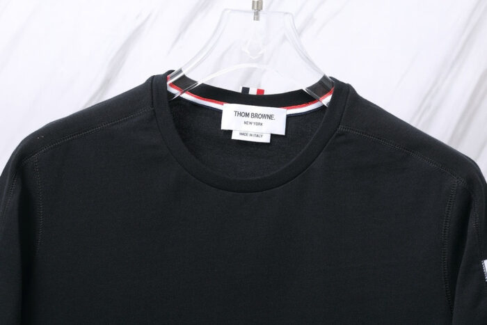 Maglietta nera Thom Browne con dettaglio colorato e logo premium, stile minimalista e versatile.