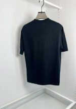 Maglietta nera semplice su appendiabiti, stile minimalista e moderno.