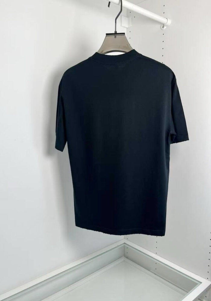 Maglietta nera semplice su appendiabiti, stile minimalista e moderno.
