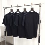 Set di quattro magliette nere minimaliste su stendibiancheria moderna e elegante.