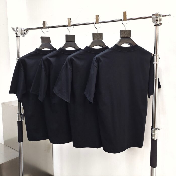 Set di quattro magliette nere minimaliste su stendibiancheria moderna e elegante.