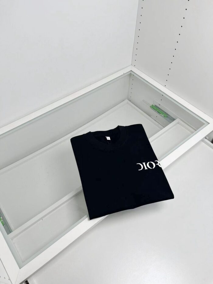 Maglietta nera minimalista con logo bianco su vetrina moderna e trasparente.
