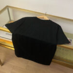 Maglietta nera casual su appendino, ambiente minimalista ed elegante con dettagli raffinati.