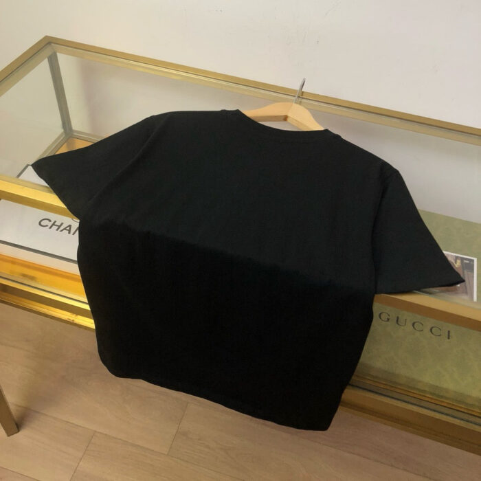 Maglietta nera casual su appendino, ambiente minimalista ed elegante con dettagli raffinati.