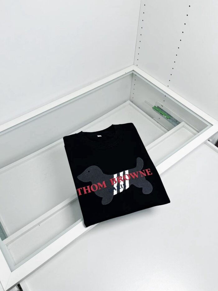 Maglietta nera con cane grafico e testo rosso in vetrina minimalista.