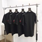 Magliette nere con ricamo, stile moderno, supporto in metallo e appendini in legno, elegante esposizione.