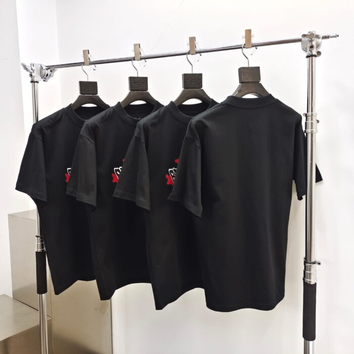 Magliette nere con ricamo, stile moderno, supporto in metallo e appendini in legno, elegante esposizione.