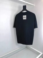 T-shirt nera minimalista appesa in armadio bianco, stile casual e design semplice.
