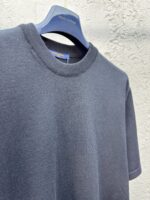 T-shirt nero casual con collo a coste su gancio, sfondo textured, stile semplice ed elegante.
