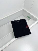 Maglietta nera minimalista in esposizione moderna con dettagli rossi e luce elegante.
