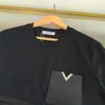 T-shirt nero con tasca geometrica e collo classico, stile elegante e versatile.