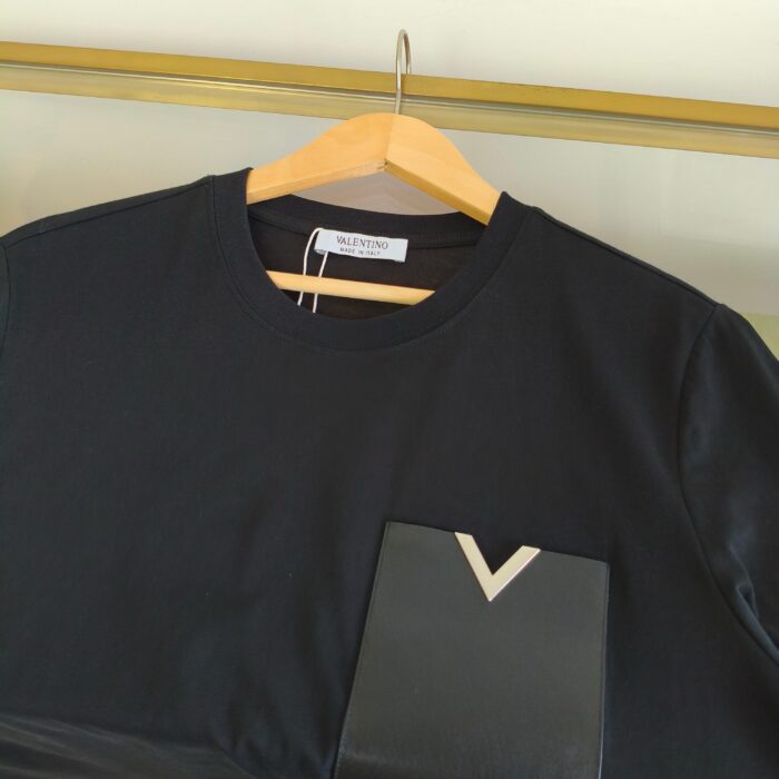 T-shirt nero con tasca geometrica e collo classico, stile elegante e versatile.