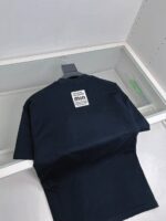Maglietta nera casual in denim navy, riflessa su vetro, stile minimalista e di qualità.