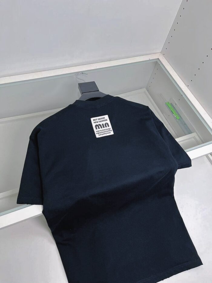 Maglietta nera casual in denim navy, riflessa su vetro, stile minimalista e di qualità.