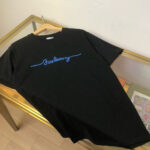 T-shirt nero con scritta ricamata blu Sundays su tavolo di vetro, stile casual e moderno.