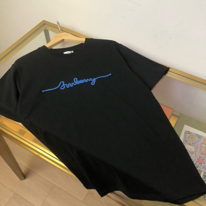 T-shirt nero con scritta ricamata blu Sundays su tavolo di vetro, stile casual e moderno.