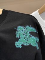 Maglietta nera con grafica teal astratta e dettagli distressed, stile streetwear moderno e versatile.