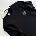 Maglietta nera minimalista con logo bianco, design elegante e stile casual moderno.