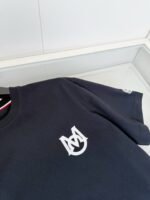 Maglietta nera con logo bianco interlacciato, stile minimal e raffinato in esposizione elegante.