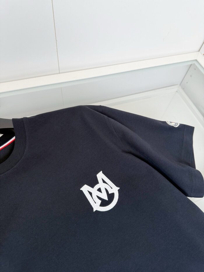 Maglietta nera con logo bianco interlacciato, stile minimal e raffinato in esposizione elegante.