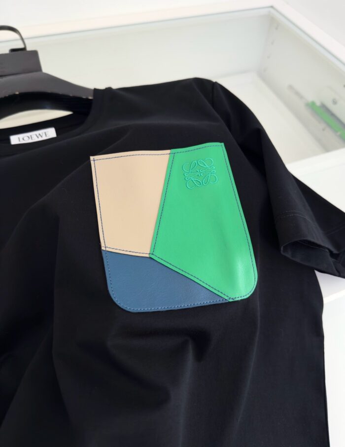 T-shirt nera con tasca colorata in geometriche tonalità, stile moderno e dettagli raffinati.