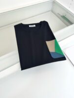 T-shirt nera con tasca geometrica colorata, stile moderno e elegante, perfetta per il casual chic.