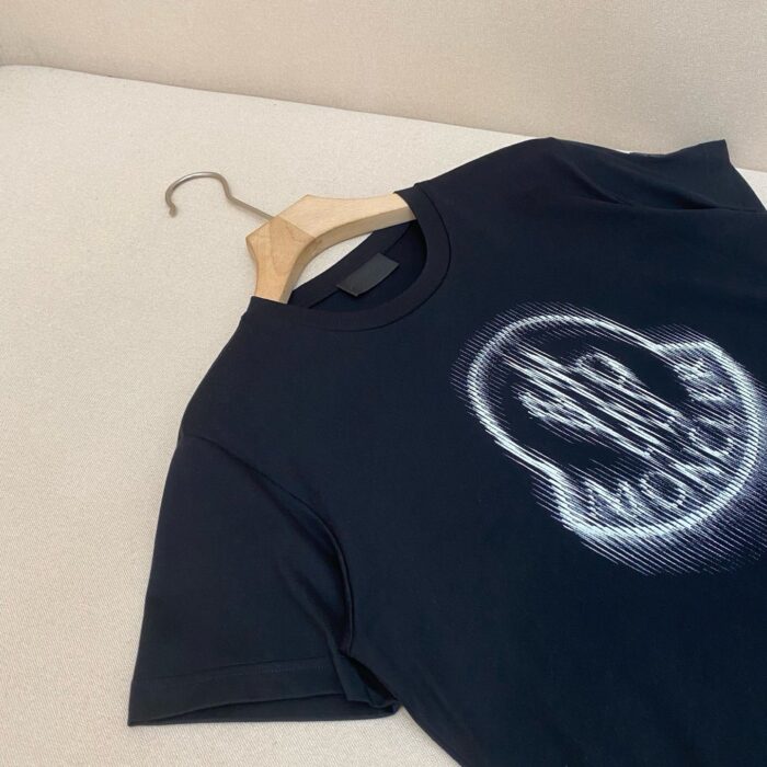 Maglietta nera con stampa urbana, su gancio di legno, stile casual e moderno.