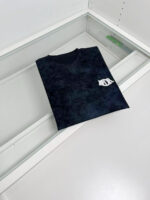 T-shirt nera con logo minimalista in esposizione elegante su supporto moderno.