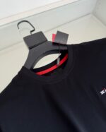 Maglietta nera con collo roccio interno rosso e logo elegante, stile casual e moderno.