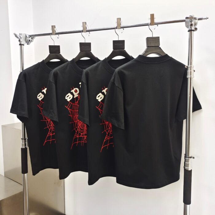 T-shirt neri con web di ragno rosso, stile streetwear, in esposizione moderna e minimalista.
