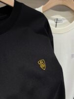 Felpe nere e bianche casual con logo scudo giallo, stile streetwear versatile e minimalista.