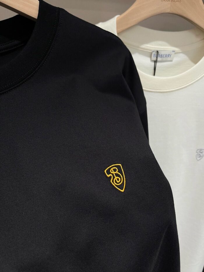 Felpe nere e bianche casual con logo scudo giallo, stile streetwear versatile e minimalista.