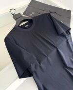 Maglietta nera minimalista in tessuto leggero, stile versatile e moderno, con borsa Zara sullo sfondo.