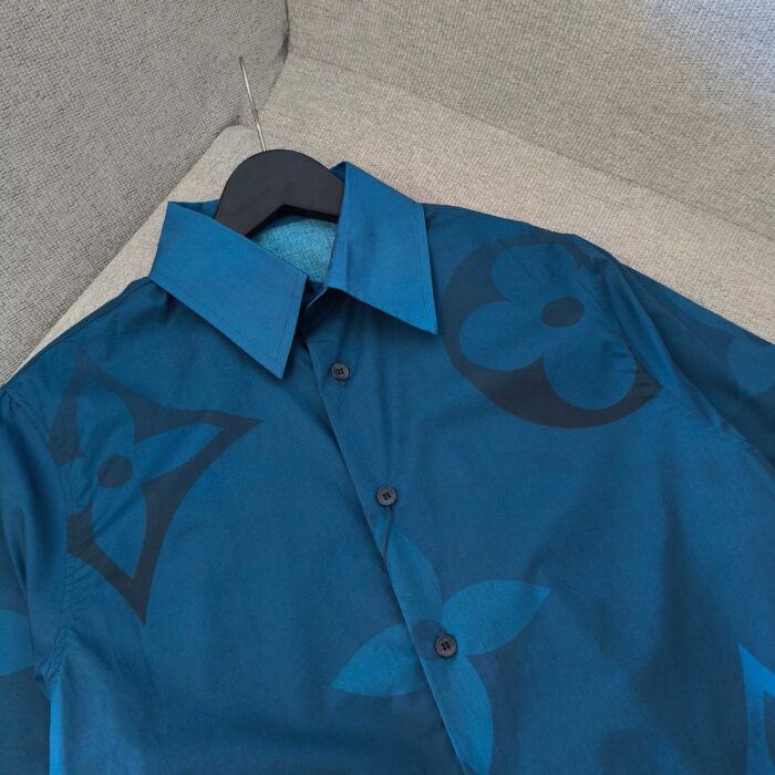 Camicia teal con motivi floreali e logo, stile elegante e versatile per ogni occasione.