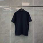 Maglietta polo blu scuro su stendino in ambiente minimalista con pareti grigie.