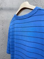 Maglietta blu a strisce casual su appendiabiti di legno, perfetta per look informali.