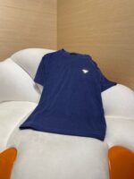Maglietta blu casual su poltrona bianca con dettagli arancioni, stile rilassato e moderno.
