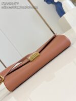 Borsa beige in pelle con chiusura oro, elegante e versatile, su superficie riflettente.