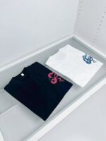 T-shirt nero e bianco con design di serpente colorato, stile moderno e contrasto vivace.