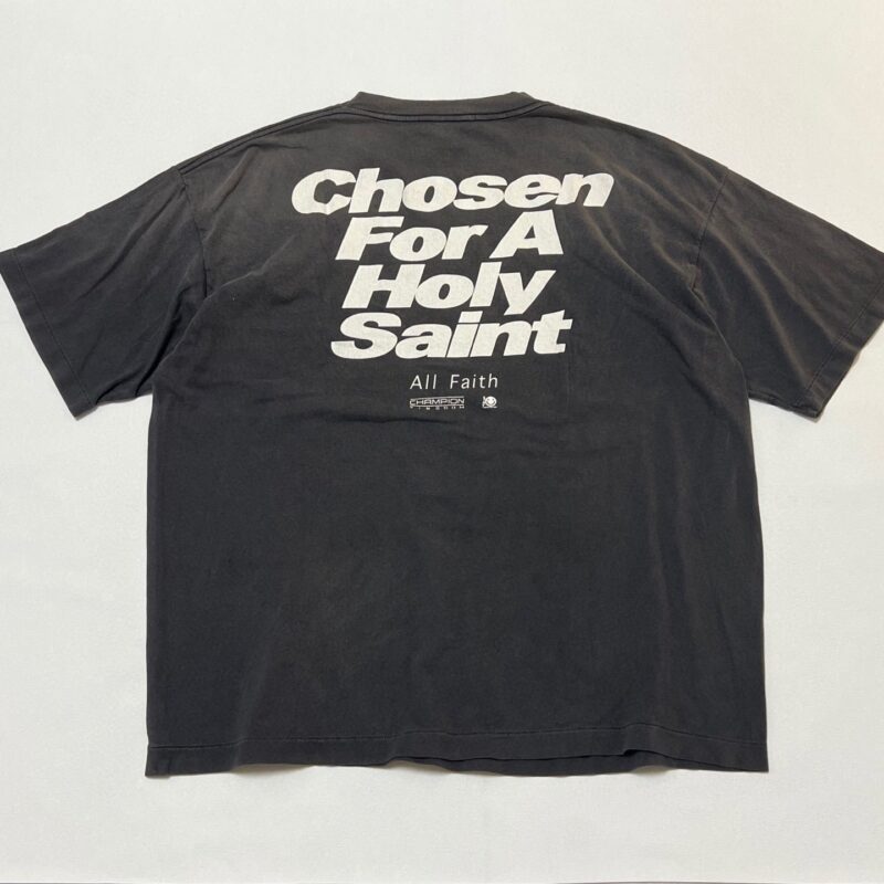 Maglietta nera streetwear con scritta bianca Chosen For A Holy Saint e All Faith.